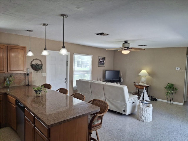 kitchen featuring hanging light fixtures, stainless steel dishwasher, a kitchen bar, and kitchen peninsula