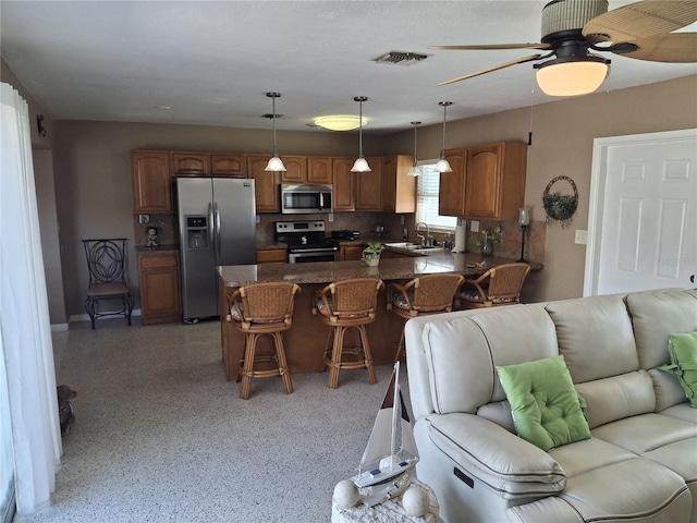 kitchen featuring a breakfast bar, sink, hanging light fixtures, kitchen peninsula, and stainless steel appliances