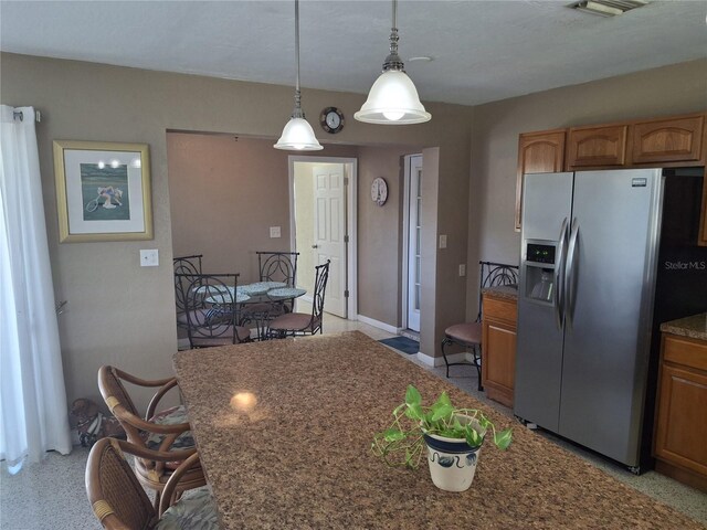 kitchen with stainless steel refrigerator with ice dispenser, a kitchen bar, and pendant lighting