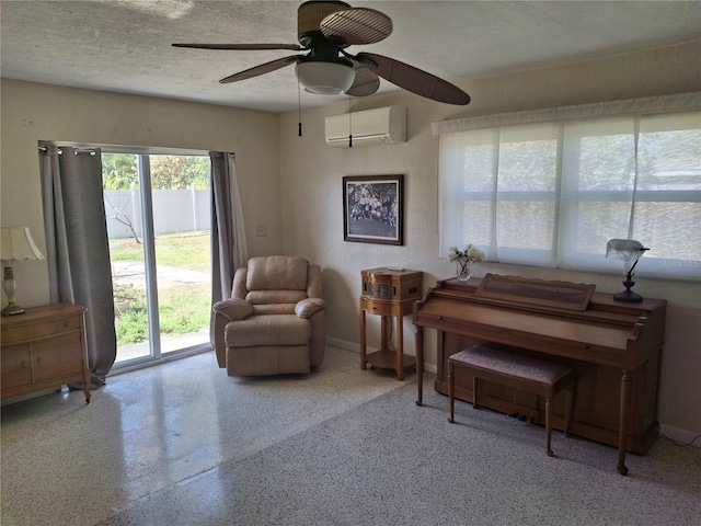 sitting room with ceiling fan, a textured ceiling, and a wall unit AC