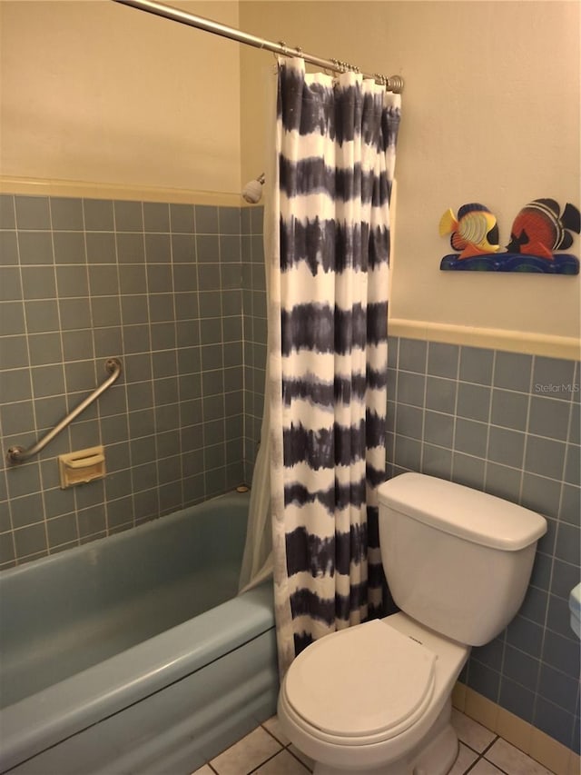 bathroom with tile patterned flooring, tile walls, shower / tub combo with curtain, and toilet