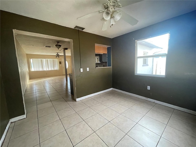 tiled spare room featuring ceiling fan