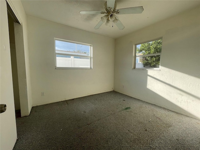 carpeted empty room with ceiling fan and plenty of natural light