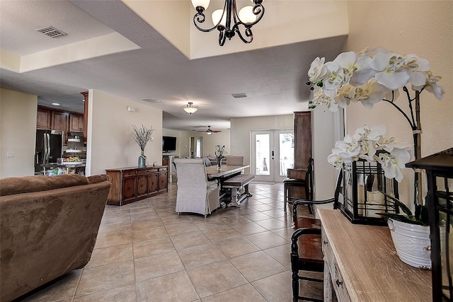 dining area featuring light tile patterned floors, a raised ceiling, ceiling fan with notable chandelier, and french doors