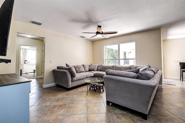 living room featuring ceiling fan, a textured ceiling, and tile patterned flooring