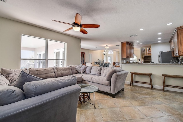 living room with ceiling fan and a textured ceiling