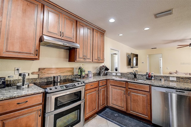 kitchen featuring appliances with stainless steel finishes, sink, ceiling fan, light tile patterned floors, and stone counters