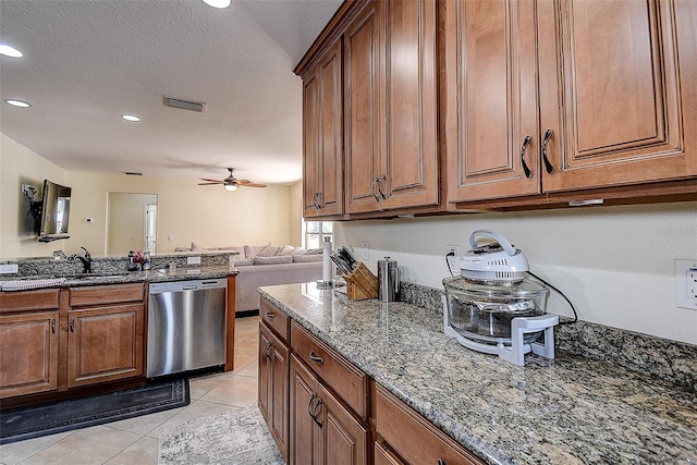 kitchen featuring ceiling fan, stainless steel dishwasher, light tile patterned flooring, a textured ceiling, and dark stone counters