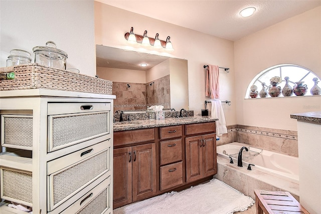 bathroom with a textured ceiling, vanity, and separate shower and tub