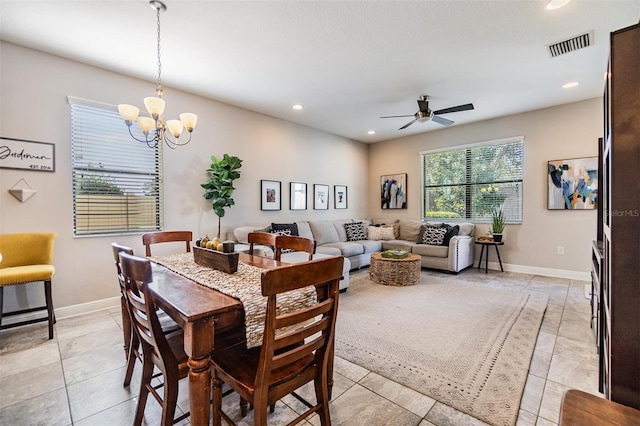 dining space with light tile patterned flooring and ceiling fan with notable chandelier