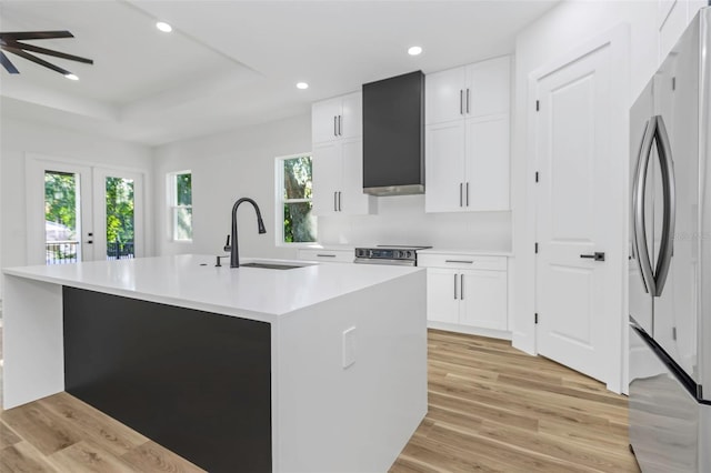 kitchen with a tray ceiling, white cabinets, stainless steel appliances, and an island with sink