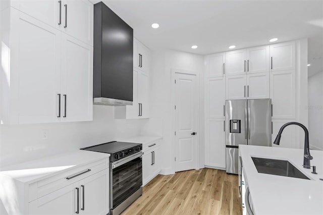 kitchen with white cabinets, sink, stainless steel appliances, and light hardwood / wood-style floors