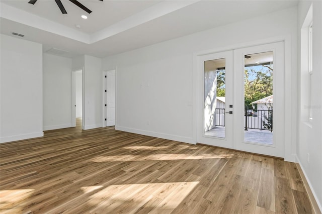 spare room with hardwood / wood-style flooring, ceiling fan, french doors, and a tray ceiling