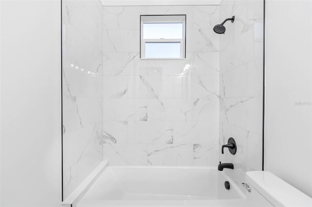 bathroom with toilet and tiled shower / bath combo