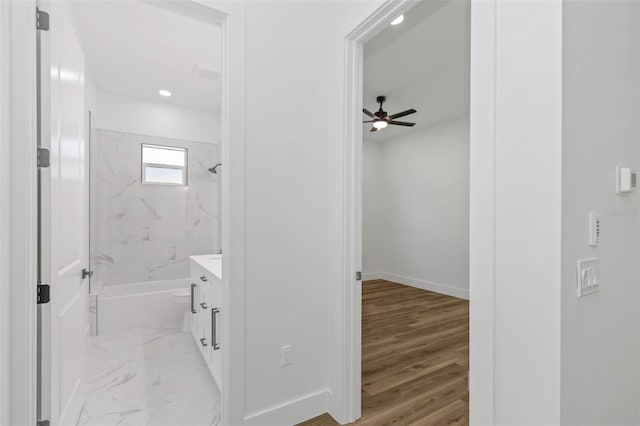 bathroom with ceiling fan, hardwood / wood-style floors, vanity, and tiled shower / bath