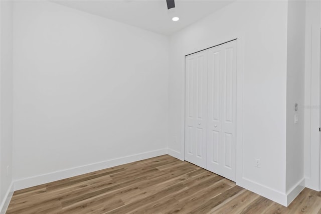 unfurnished bedroom with ceiling fan, wood-type flooring, and a closet