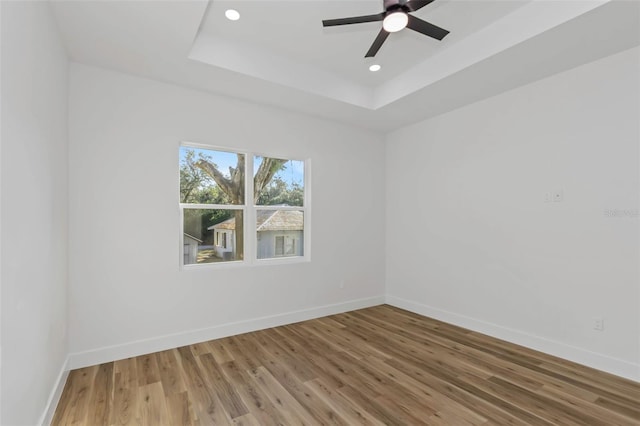 spare room featuring hardwood / wood-style flooring, ceiling fan, and a raised ceiling