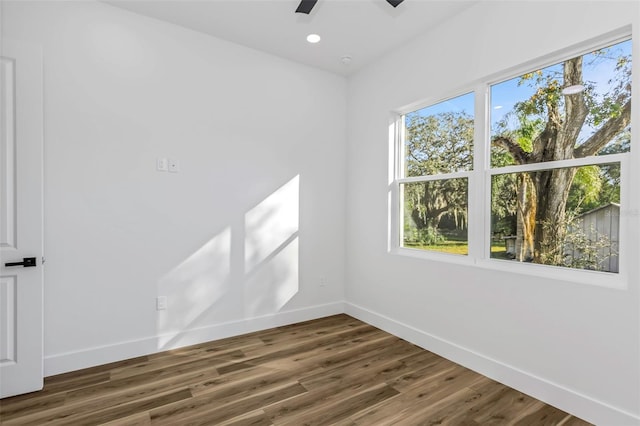 empty room with ceiling fan, plenty of natural light, and dark hardwood / wood-style floors