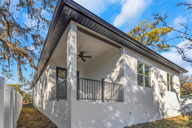 view of side of home with ceiling fan and a balcony