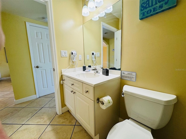 bathroom with tile patterned flooring, baseboards, vanity, and toilet