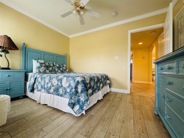 bedroom with arched walkways, ceiling fan, wood finished floors, baseboards, and ornamental molding