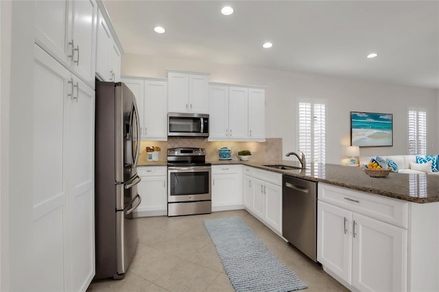 kitchen featuring stainless steel appliances, dark stone countertops, white cabinets, and sink