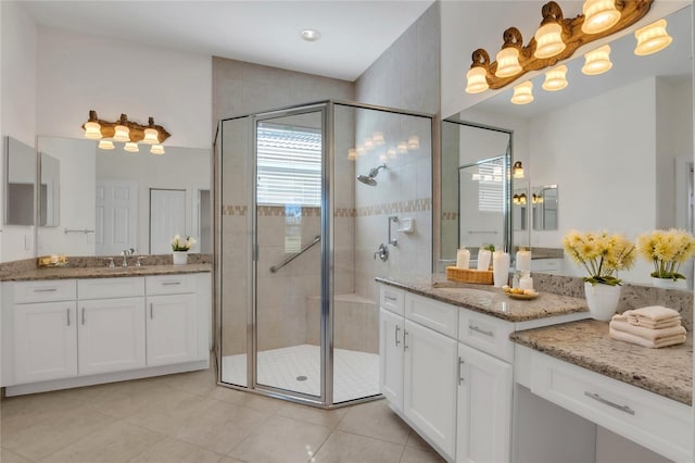 bathroom featuring tile patterned flooring, a shower with shower door, and vanity