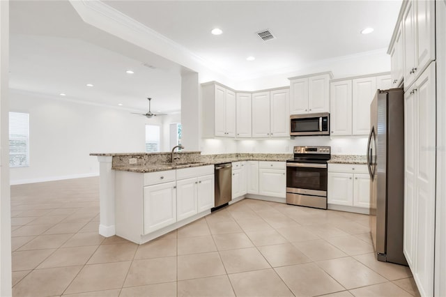 kitchen featuring light stone countertops, stainless steel appliances, kitchen peninsula, and white cabinets