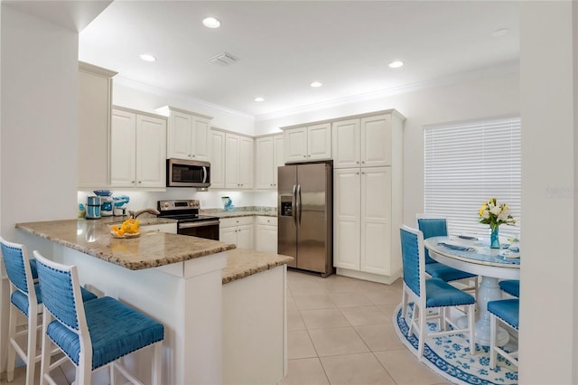 kitchen featuring white cabinetry, kitchen peninsula, stainless steel appliances, crown molding, and light stone countertops