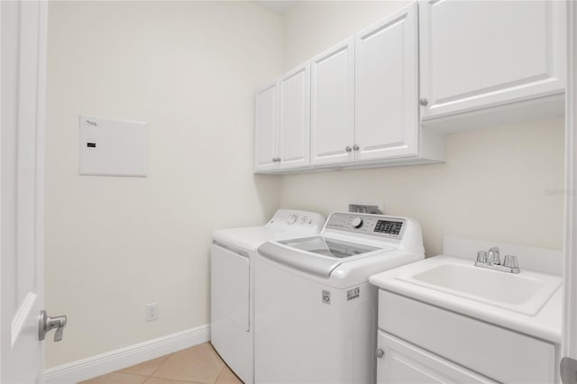 clothes washing area with cabinets, washer and clothes dryer, sink, and light tile patterned floors