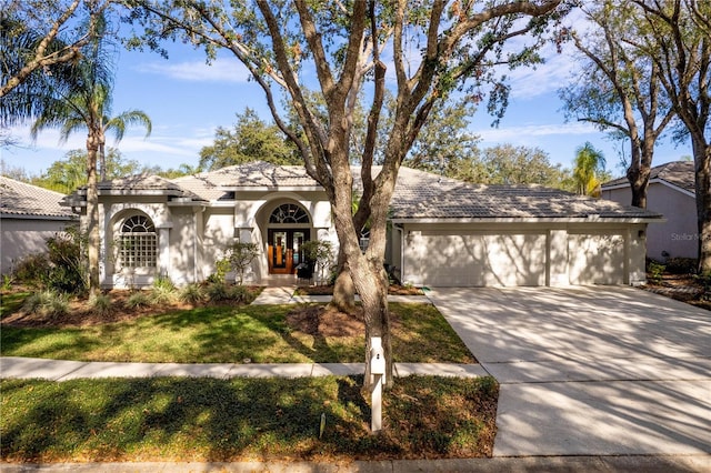 view of front of house featuring an attached garage, a tile roof, concrete driveway, and stucco siding