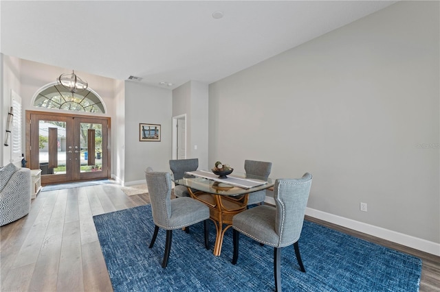 dining space with french doors, an inviting chandelier, and hardwood / wood-style flooring