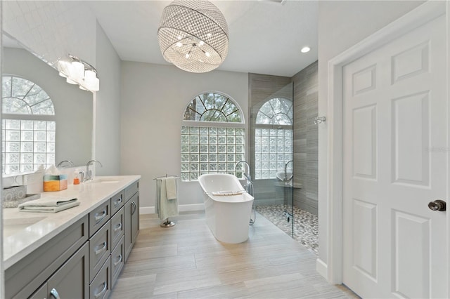 bathroom with plenty of natural light, an inviting chandelier, plus walk in shower, and vanity