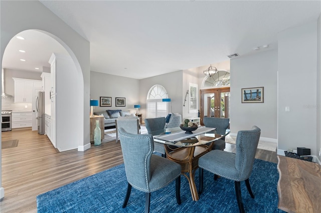 dining room featuring french doors, a notable chandelier, and light hardwood / wood-style flooring