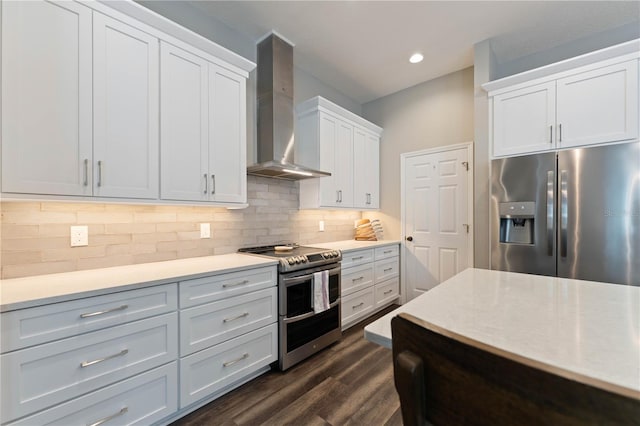 kitchen featuring stainless steel appliances, white cabinets, wall chimney exhaust hood, decorative backsplash, and dark hardwood / wood-style flooring