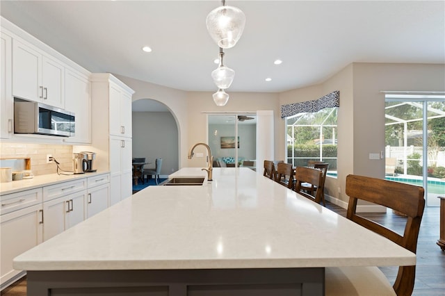 kitchen with a large island, pendant lighting, white cabinets, and backsplash