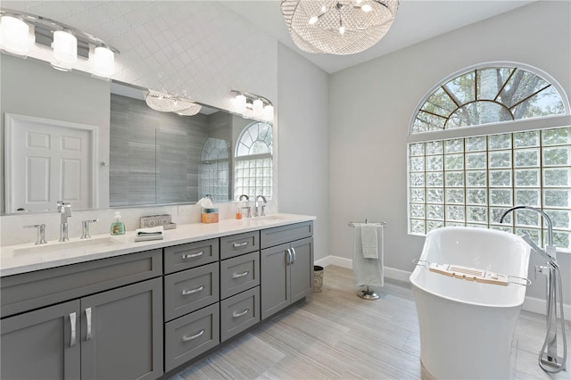 bathroom featuring a chandelier, plus walk in shower, and vanity