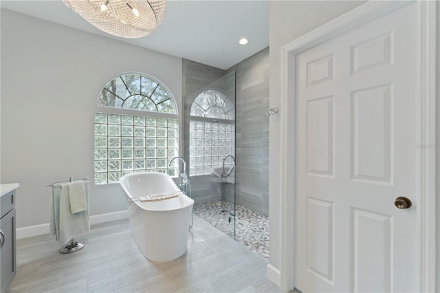 bathroom with a notable chandelier, separate shower and tub, and vanity