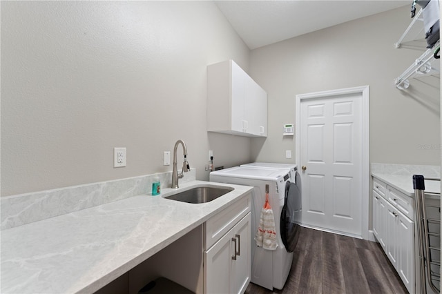 washroom featuring sink, dark wood-type flooring, cabinets, and washer and clothes dryer