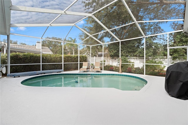 view of pool with a patio area, grilling area, and glass enclosure