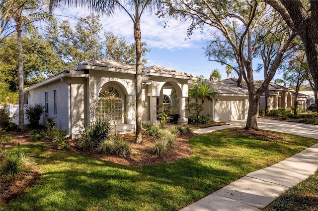 mediterranean / spanish-style home featuring a front yard, driveway, an attached garage, and stucco siding