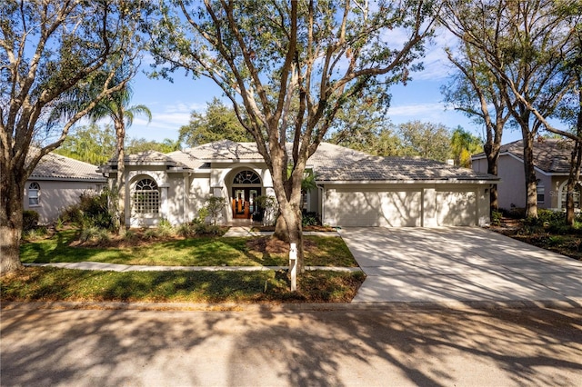 view of front of home with a garage, concrete driveway, a tiled roof, and stucco siding