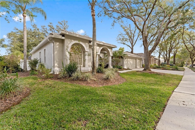 mediterranean / spanish-style house with a garage, stucco siding, driveway, and a front yard