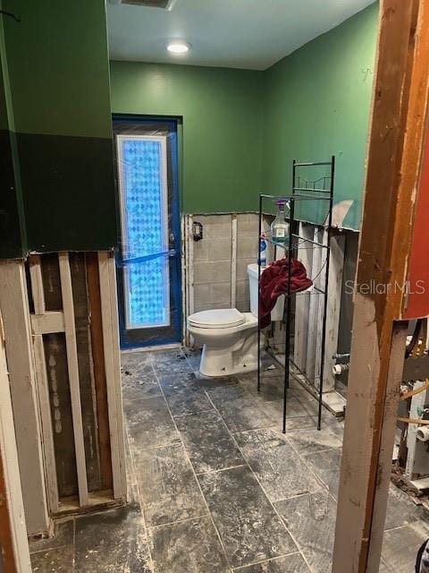 bathroom with toilet and tile walls