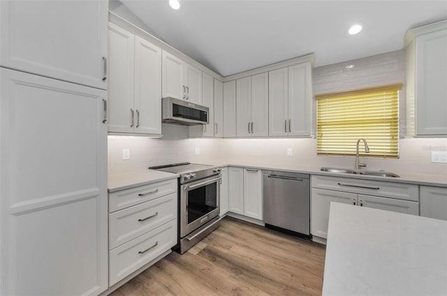 kitchen with sink, white cabinetry, tasteful backsplash, light hardwood / wood-style flooring, and stainless steel appliances