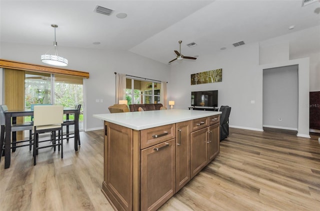 kitchen with lofted ceiling, a center island, hanging light fixtures, ceiling fan, and light hardwood / wood-style floors