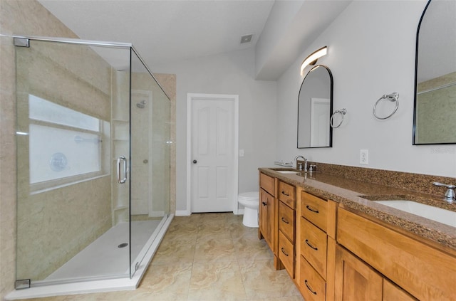 bathroom featuring a shower with door, vanity, and toilet