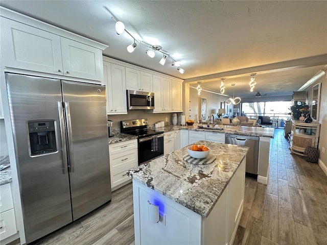 kitchen featuring light hardwood / wood-style floors, kitchen peninsula, white cabinets, and stainless steel appliances