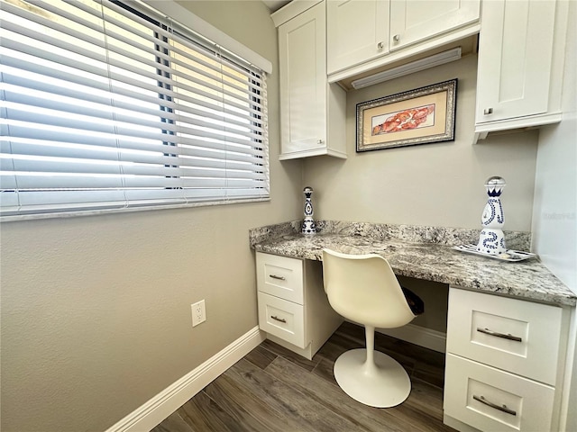 office with dark hardwood / wood-style flooring and built in desk