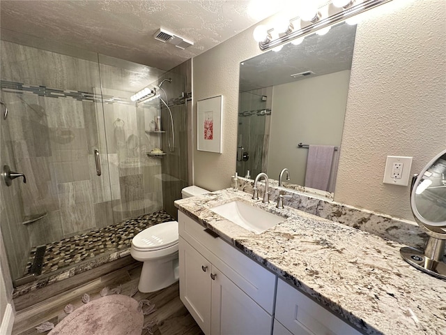 bathroom featuring hardwood / wood-style floors, a textured ceiling, an enclosed shower, vanity, and toilet